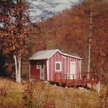 A small red house in the woods

Description automatically generated